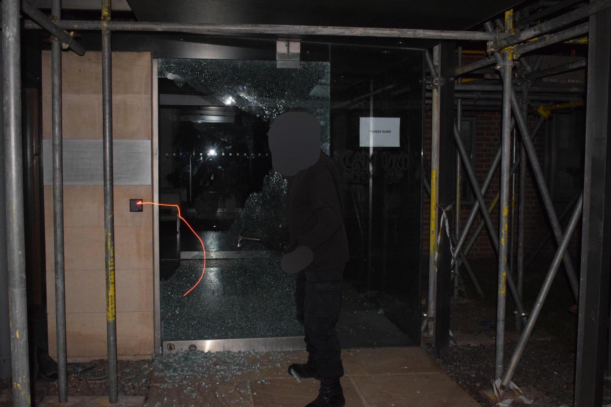 A climate activist smashes the glass door at the BP Institute, University of Cambridge.
